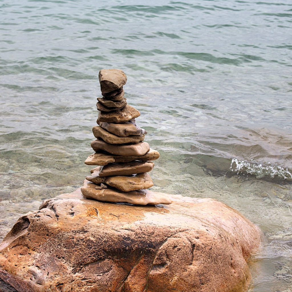 balanced-rocks-lake-michigan-wave-view flat rocks balanced on large boulders in lake michigan with a wave