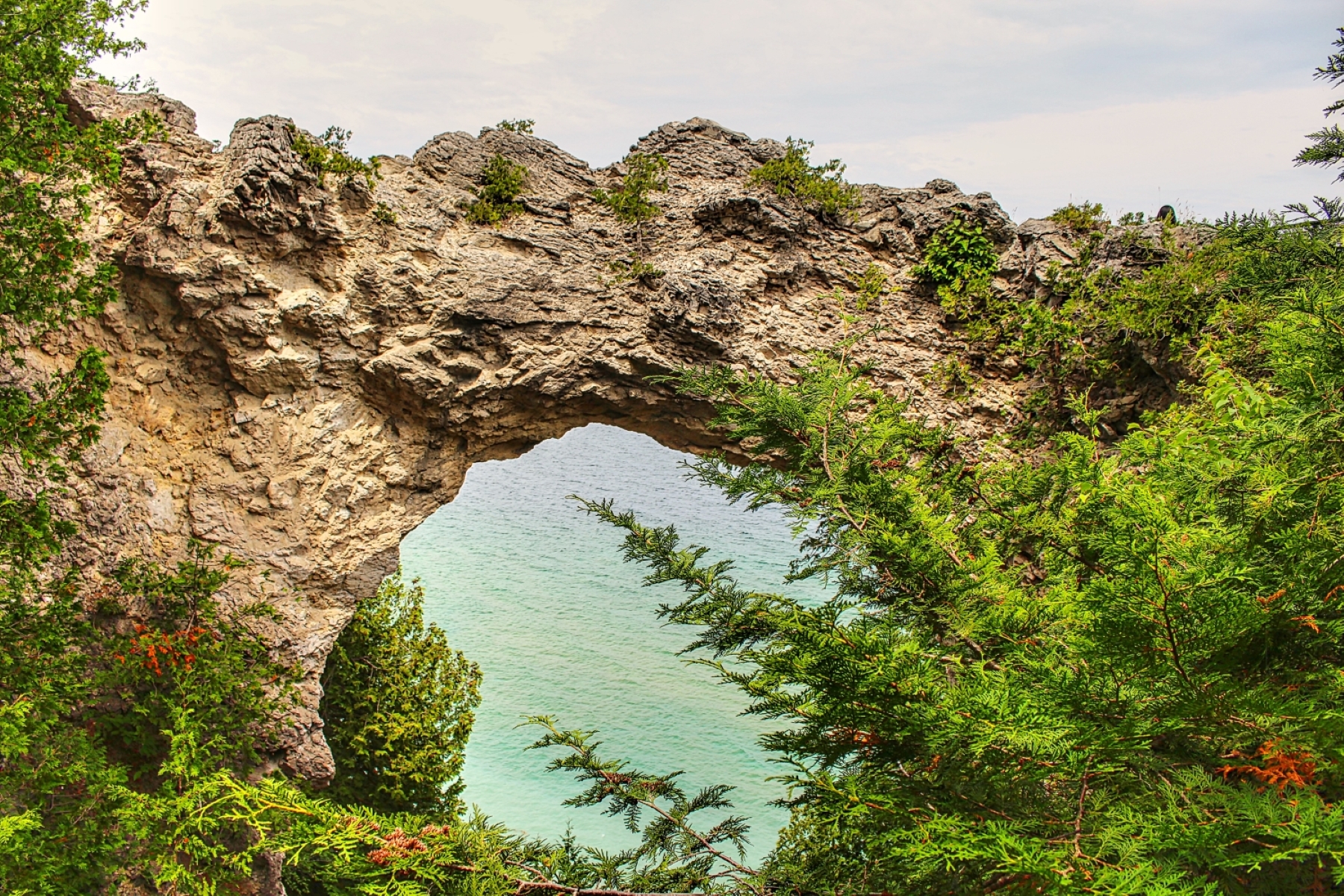 large arch rock with a hole in the middle looking down on blue lake huron