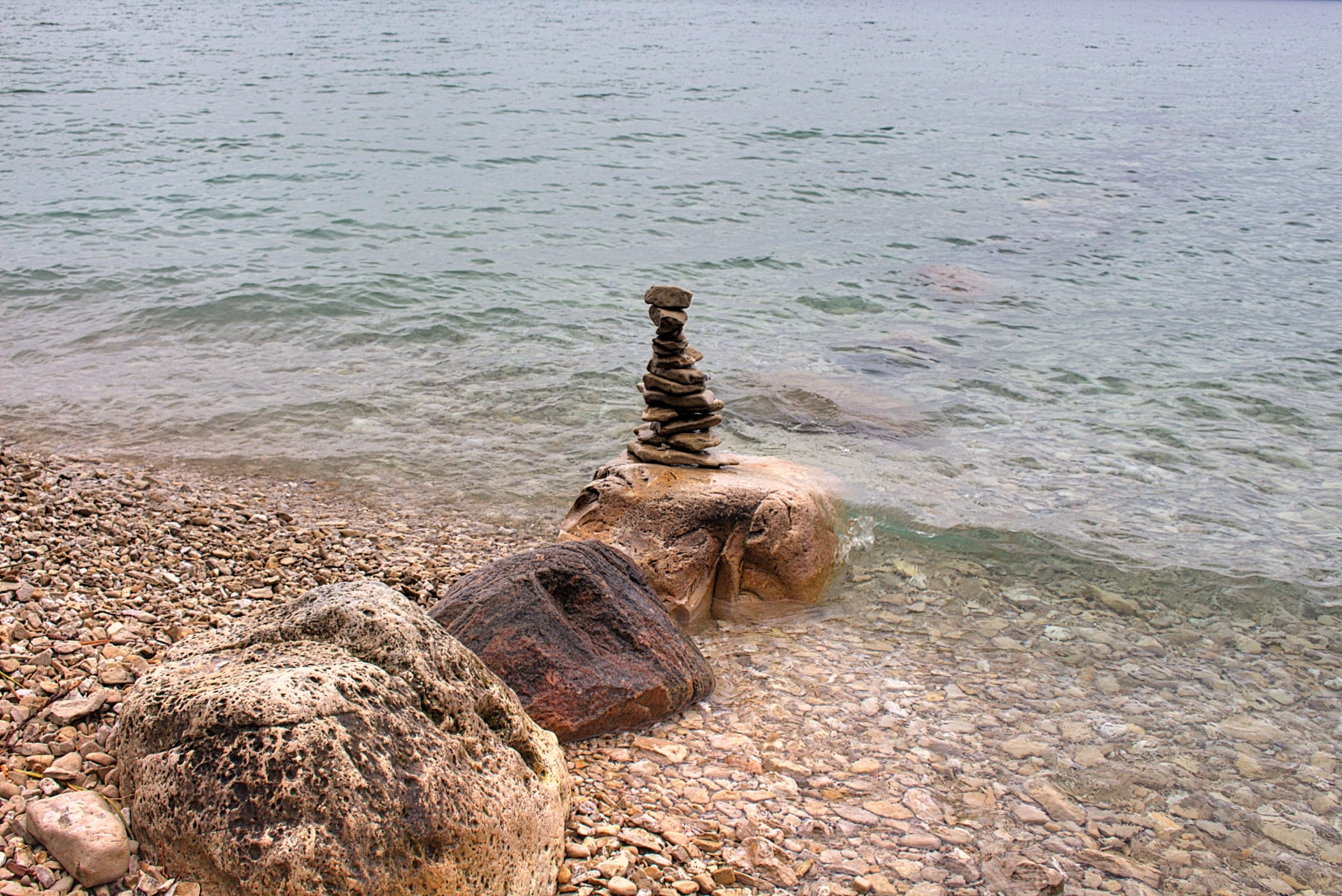 three large boulders going out into lake michigan with balanced rocks on the last one
